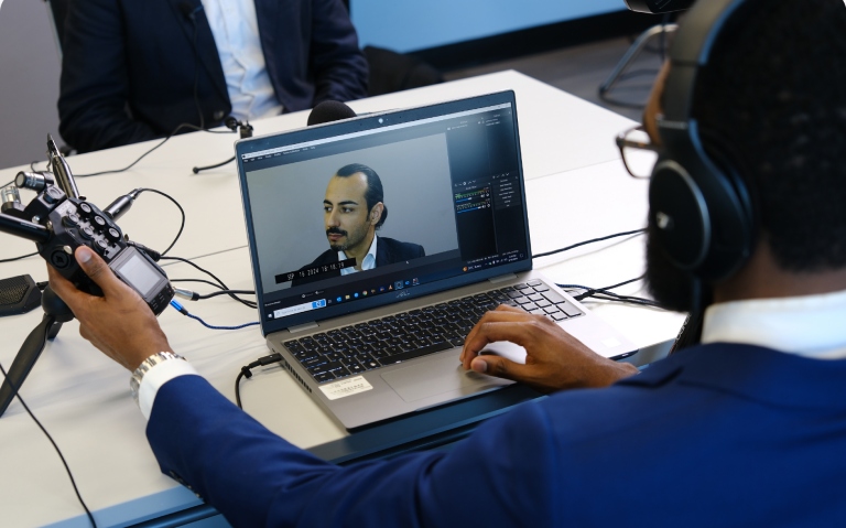 Videographer adjusts equipment during deposition, recording deponent