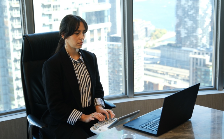 A court reporter types on a stenograph